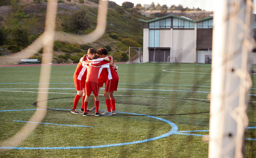 High school soccer players in huddle on the field