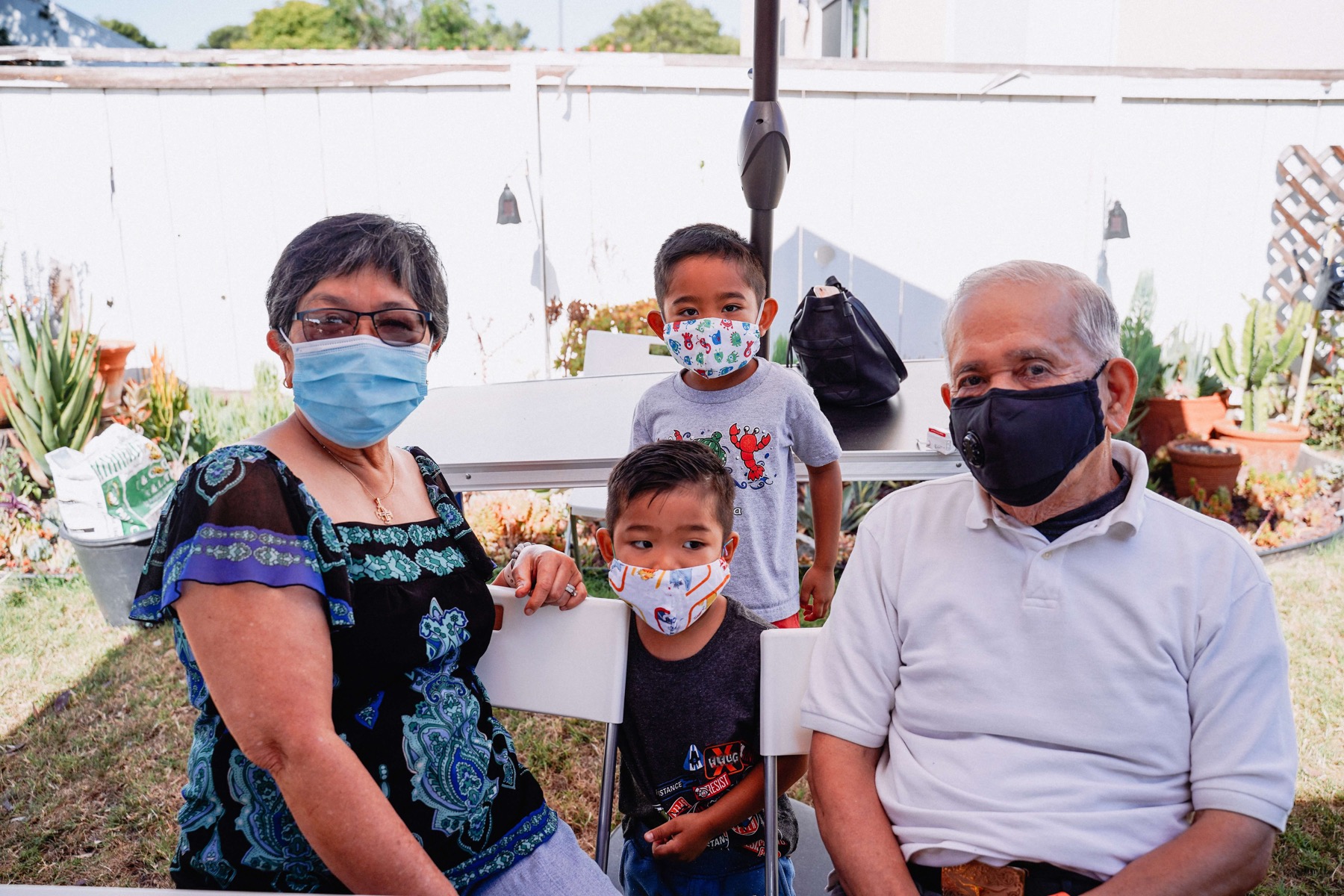 Generational family sitting outdoors wearing protective masks