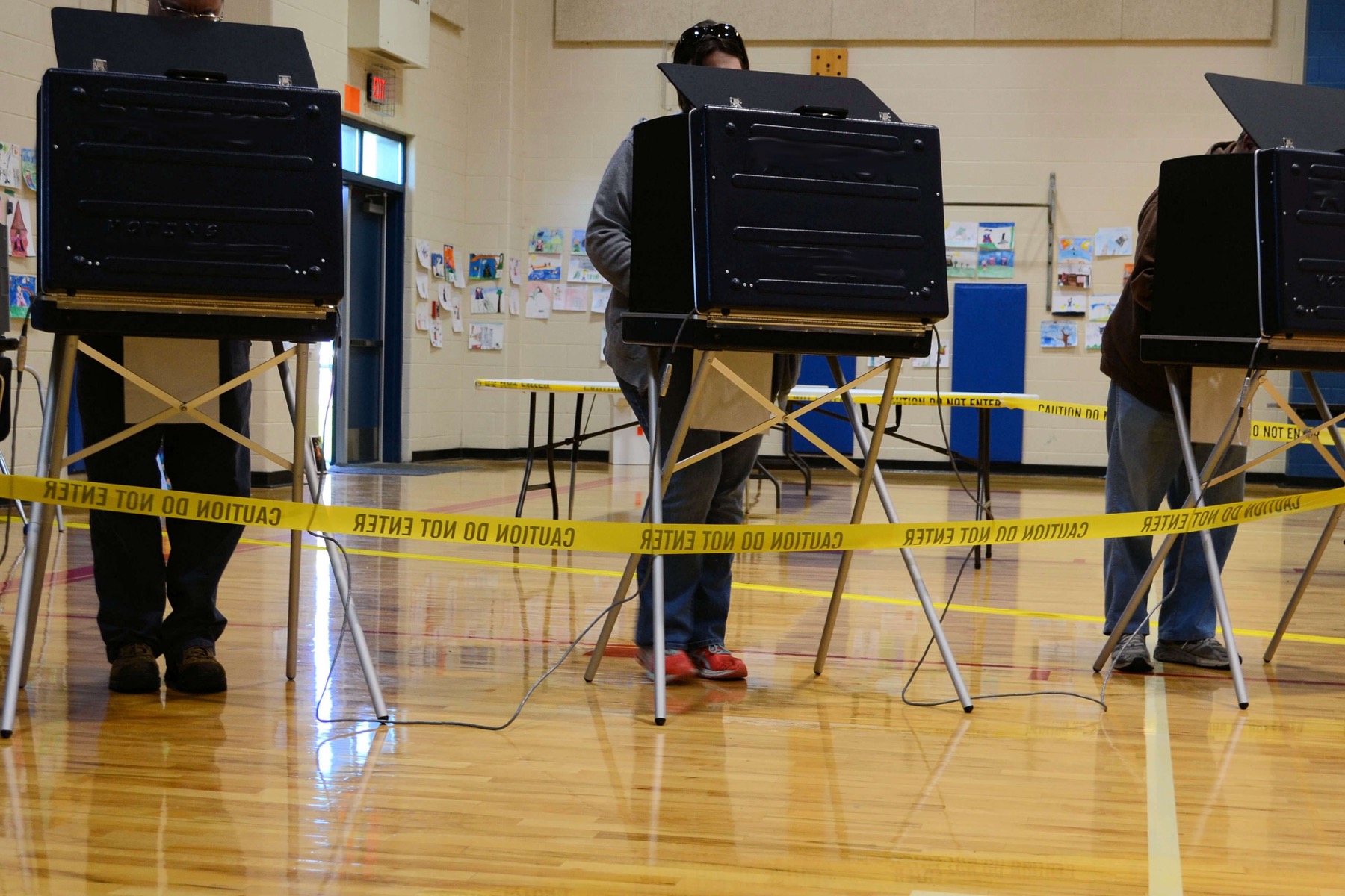 people using voting booths in a school gym