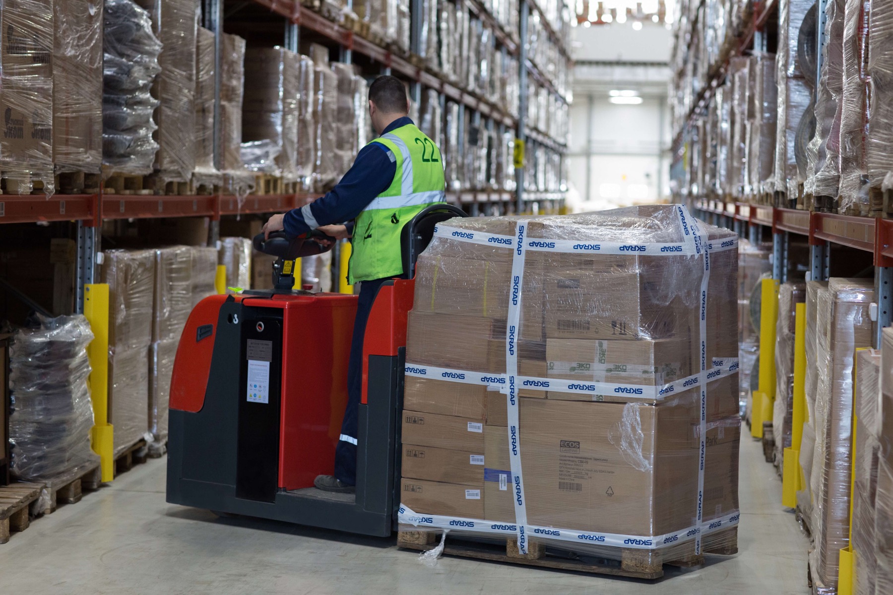 warehouse worker transporting a pallet of cardboard boxes