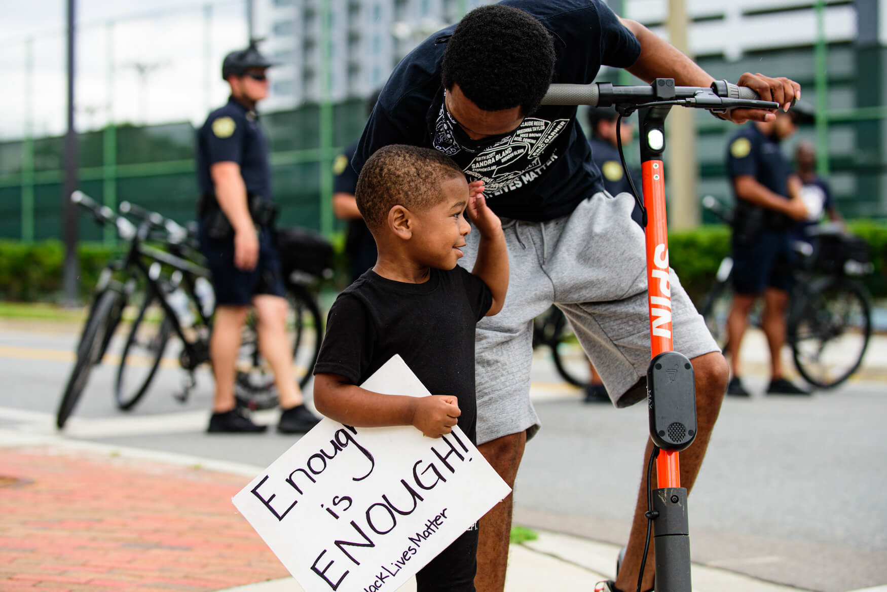 Black father and son at Black Lives Matter demonstration with sign reading "Enough is Enough"