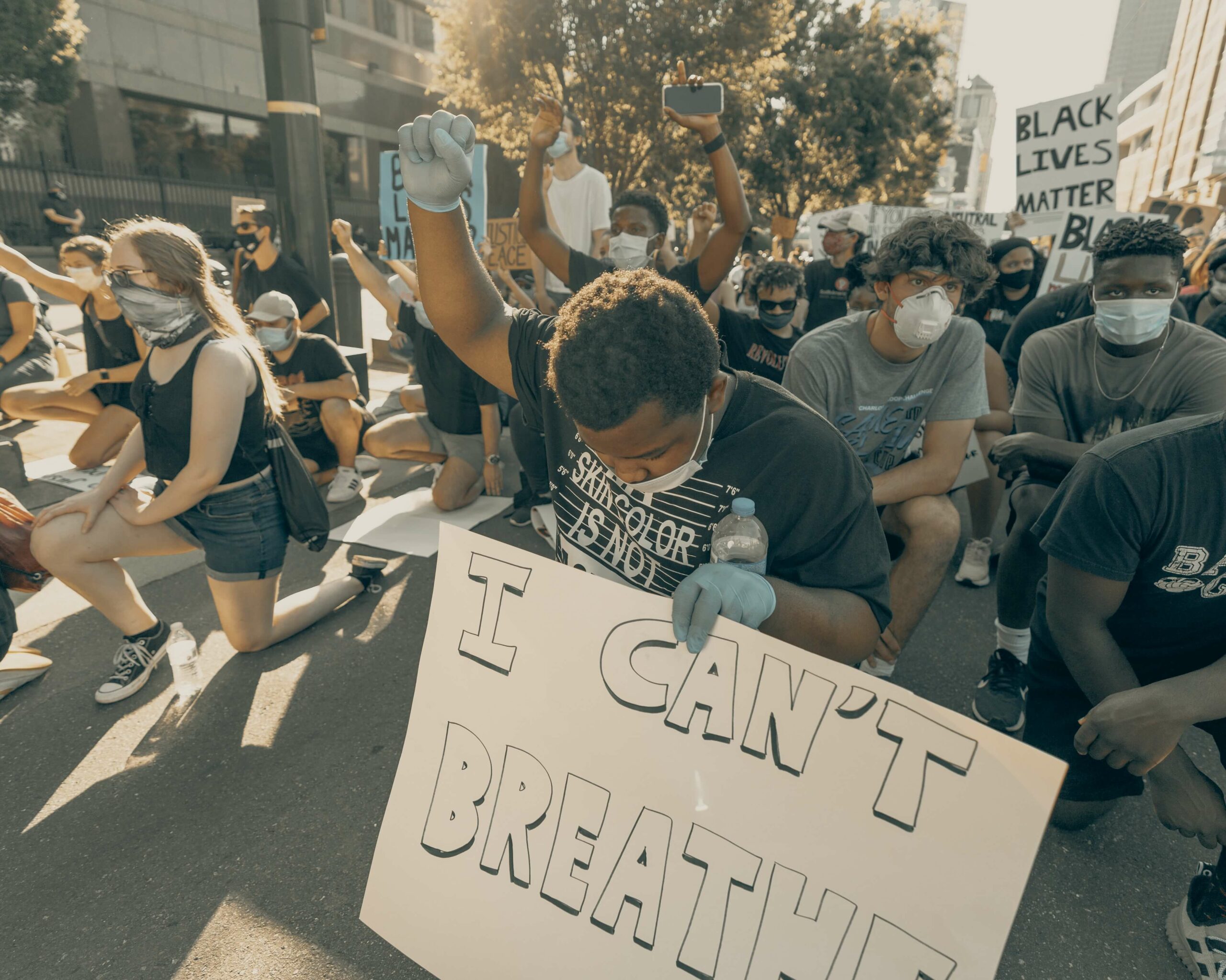 Protestor holding up his fist in solidarity; Photo by Clay Banks