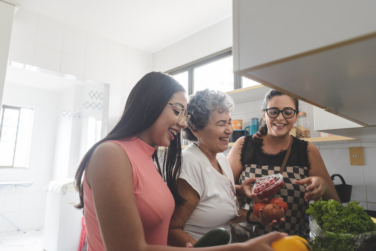 Latina grandmother, mother, and daughter unpacking groceries in the kitchen