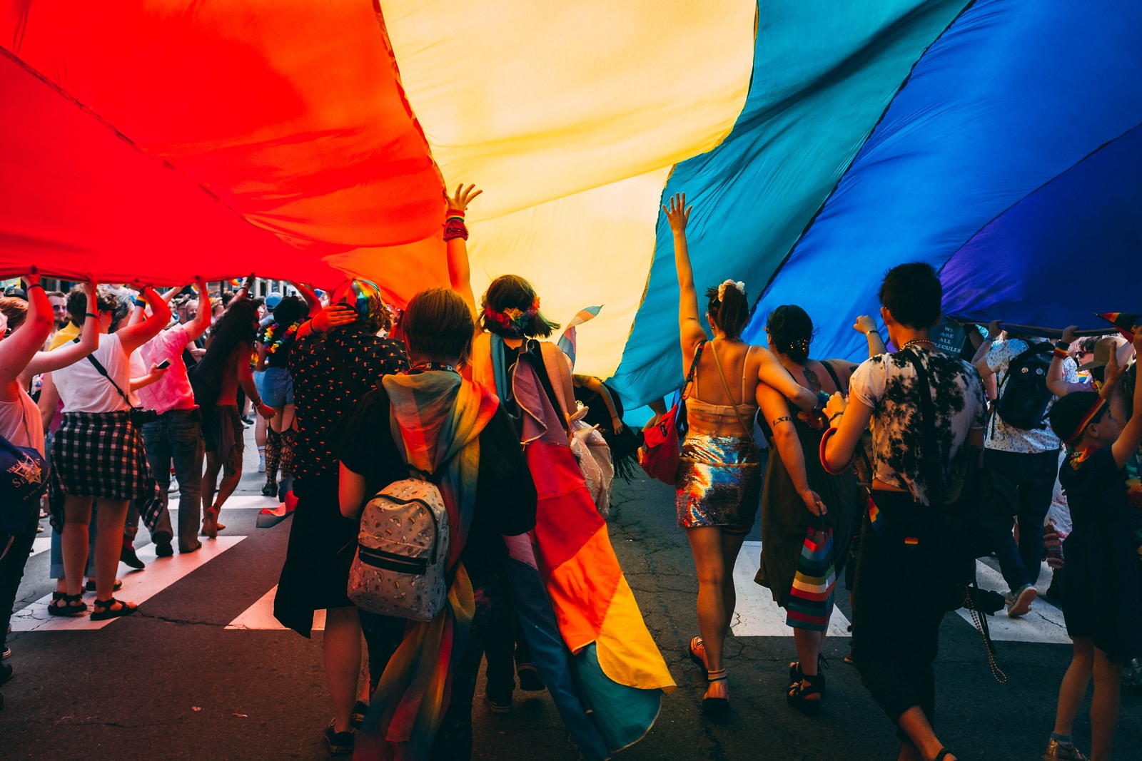 Group of people under rainbow flag at Pride parade