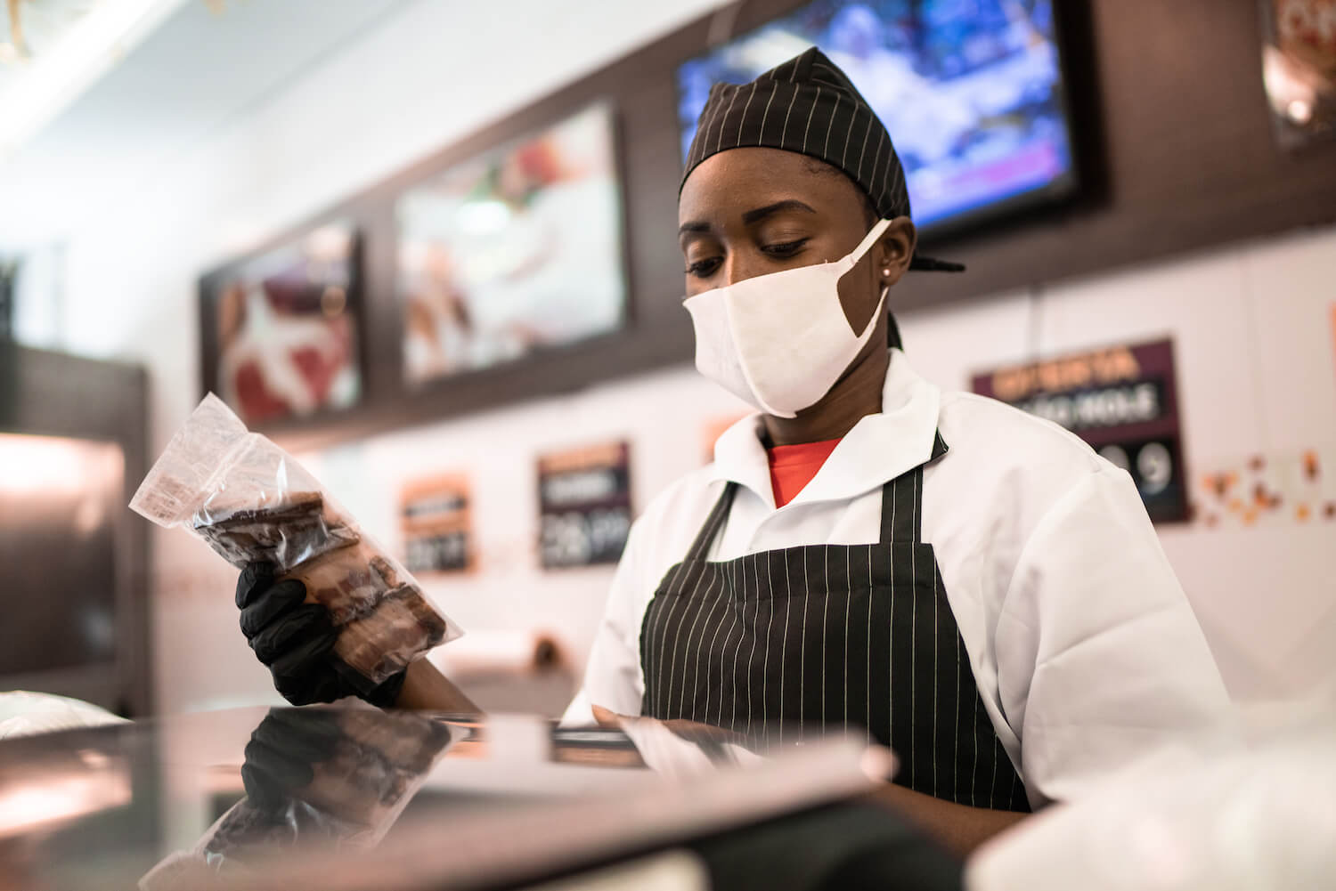 Black butcher talking to customer at butchers shop